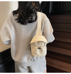Detailed view of the functional drawstring front pocket on this beige canvas crossbody bag