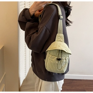 Detail of light green checkered crossbody bag with adjustable strap and drawstring closure