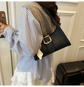 Détail du sac baguette noir motif crocodile avec boucle dorée et foulard en soie