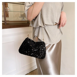 Détail du sac à bandoulière à paillettes noires avec chaîne dorée et texture scintillante