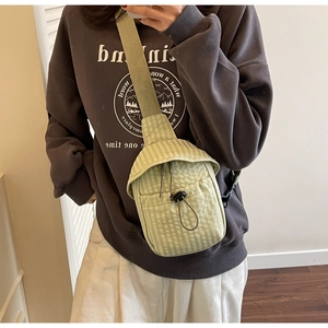 Detail of light green checkered crossbody bag with adjustable strap and drawstring pocket