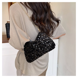 Détail d'un sac bandoulière à paillettes noires avec chaîne dorée sur mannequin