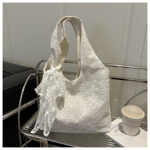 Macro shot of white lace embroidery texture and large ribbon bow on elegant tote bag