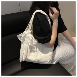 Close-up of white floral lace tote bag featuring decorative lace bow detail and embroidery