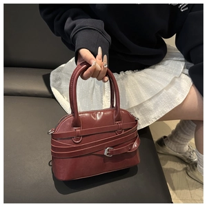 Dettaglio della borsa a tracolla rosso scuro lucida con fibbie in metallo argento