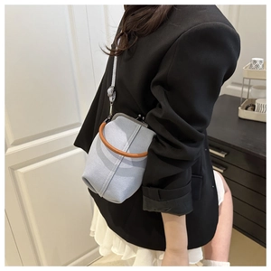 Détail du mini sac seau en denim bleu clair avec fermoir rétro et poignée tan