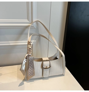 Détail du sac baguette blanc texture croco avec boucle dorée et bandoulière en soie