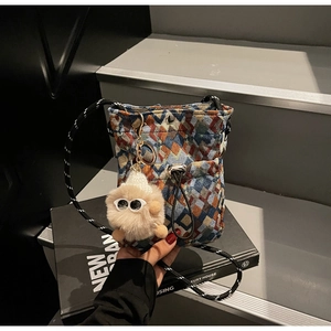 Detail of colorful geometric woven tapestry crossbody bag with a plush monster charm