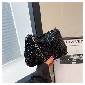 Détail d'un sac de soirée à paillettes noires avec bandoulière chaîne dorée élégante