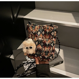 Detail of woven floral checkered mini bag featuring drawstring pocket and plush charm