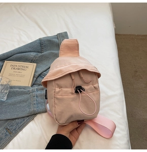 Detail of light pink mini nylon crossbody bag with drawstring closure on white bedding
