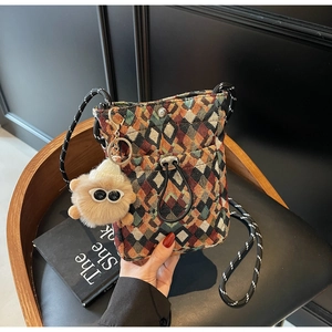 Detail of woven crossbody bag with geometric patterns and a plush doll pendant