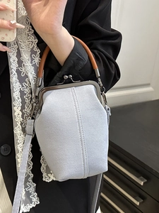Sac à main en jean bleu clair avec fermoir vintage et poignée marron porté par mannequin