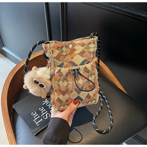 Detail of woven crossbody bag with geometric patterns and a cute plush ball charm