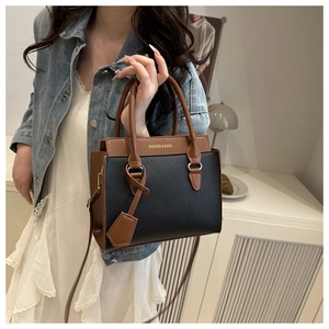 Detail of lychee textured leather tote bag with contrast stitching and golden hardware