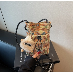 Close-up of bohemian geometric jacquard crossbody bag with a cute plush monster charm