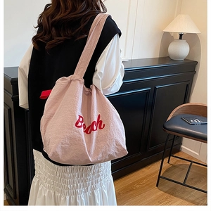 Dettaglio della borsa tote in nylon rosa con ricamo Beach rosso e tessuto operato
