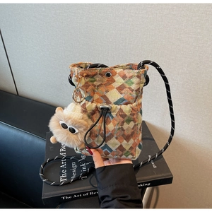 Detail of colorful geometric tweed crossbody bag with plush monster charm and rope strap