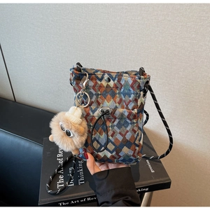 Detailed view of bohemian geometric woven crossbody bag with plush monster pendant