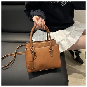 Detail of brown lychee grain leather tote bag with gold logo and detachable strap