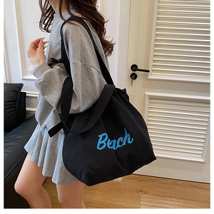 Dettaglio della borsa tote in tela nera con ricamo Beach blu e chiusura con coulisse