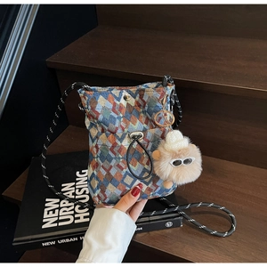 Detail of colorful geometric woven crossbody bag with a cute white plush sheep charm
