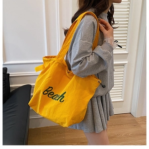 Dettaglio della grande borsa tote in tela gialla con ricamo Beach verde e coulisse