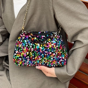 Sac bandoulière pailleté coloré avec chaîne dorée porté sur une veste grise
