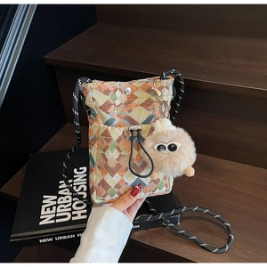 Close-up of geometric woven crossbody bag with rope strap and plush eye charm