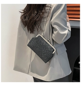 Détail d'une pochette de soirée noire à paillettes avec chaîne argentée sur un tailleur