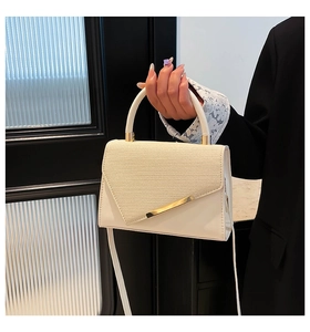 Détail du sac bandoulière crème avec texture tressée et garniture en métal doré