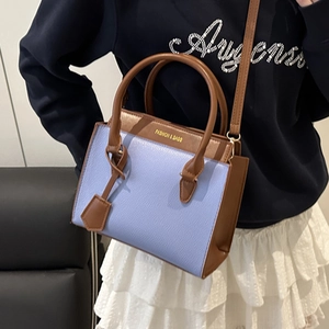 Chic blue and brown leather tote bag with long strap shown in a lifestyle setting