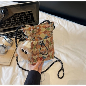 Detailed shot of woven crossbody bag with colorful geometric patterns and monster charm