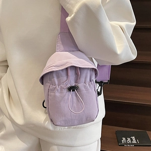 Minimalist light purple nylon crossbody bag with drawstring pocket worn by a model