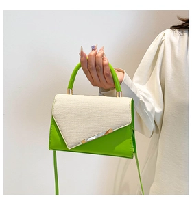 Détail du sac à main vert avec rabat tissé beige, barre métallique et poignée haute