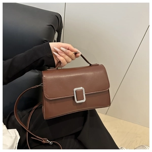 Détail du sac bandoulière en similicuir marron foncé avec boucle argentée et poignée