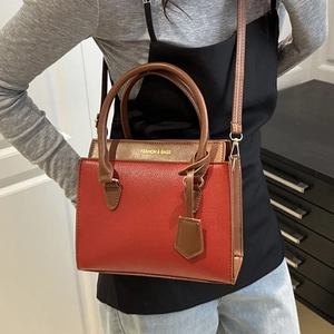 Red-brown contrast leather tote bag with top handles and adjustable shoulder strap