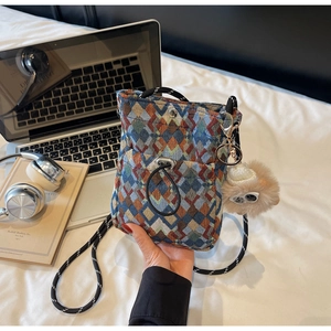 Detail of colorful geometric woven pattern and plush charm on casual mini crossbody bag