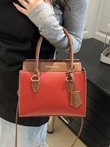 Chic red and brown leather tote bag with gold hardware shown on model in home setting
