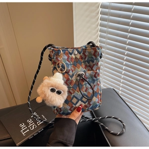 Detail of floral woven crossbody bag with colorful patterns and plush monster charm