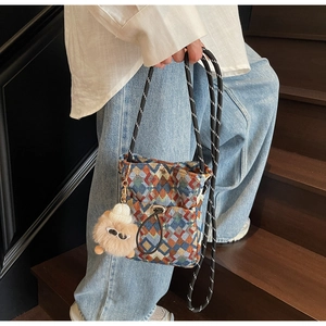Detail of colorful geometric pattern crossbody bag with a cute plush bear pendant