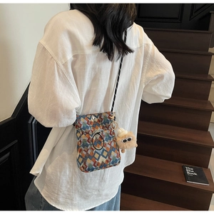 Detail of colorful geometric woven crossbody bag with cute plush pendant and lanyard