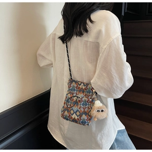 Close-up of fabric crossbody bag with colorful geometric patterns and plush charm