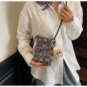Detail of patterned crossbody phone bag with cute plush monster charm on model