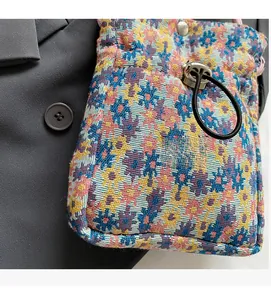 Detailed close-up of floral brocade fabric texture and drawstring buckle on a mini bag