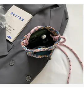 Interior view of woven drawstring bucket bag holding a smartphone and lipstick