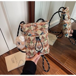 Detail of colorful geometric woven fabric bag with drawstring and plush charm accessory