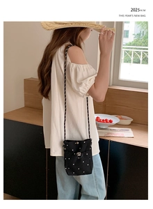 Détail d'un petit sac bandoulière en toile noire avec motifs de fleurs blanches