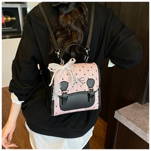 Detail des rosa Rucksacks mit Herzmuster, Spitzen-Perlen-Schleife und Lederklappe