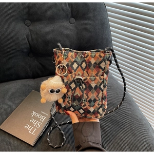 Detail of colorful geometric woven crossbody bag with a cute plush monster charm